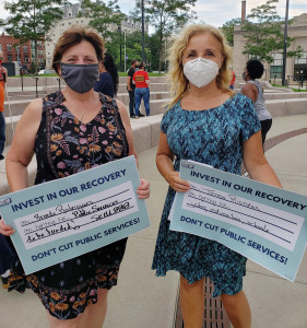 APPEAL TO LAWMAKERS: Local 888 President Brenda Rodrigues and longtime leader Teresa Riordan hold signs at a Brockton rally warning that deep budget cuts could drive the state into a deeper recession. The Coalition for Social Justice and Raise Up Massachusetts organized the event.