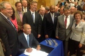 Governor Deval Patrick signs a minimum wage bill that passed largely as a result of the work of grassroots activists including many Local 888 members.